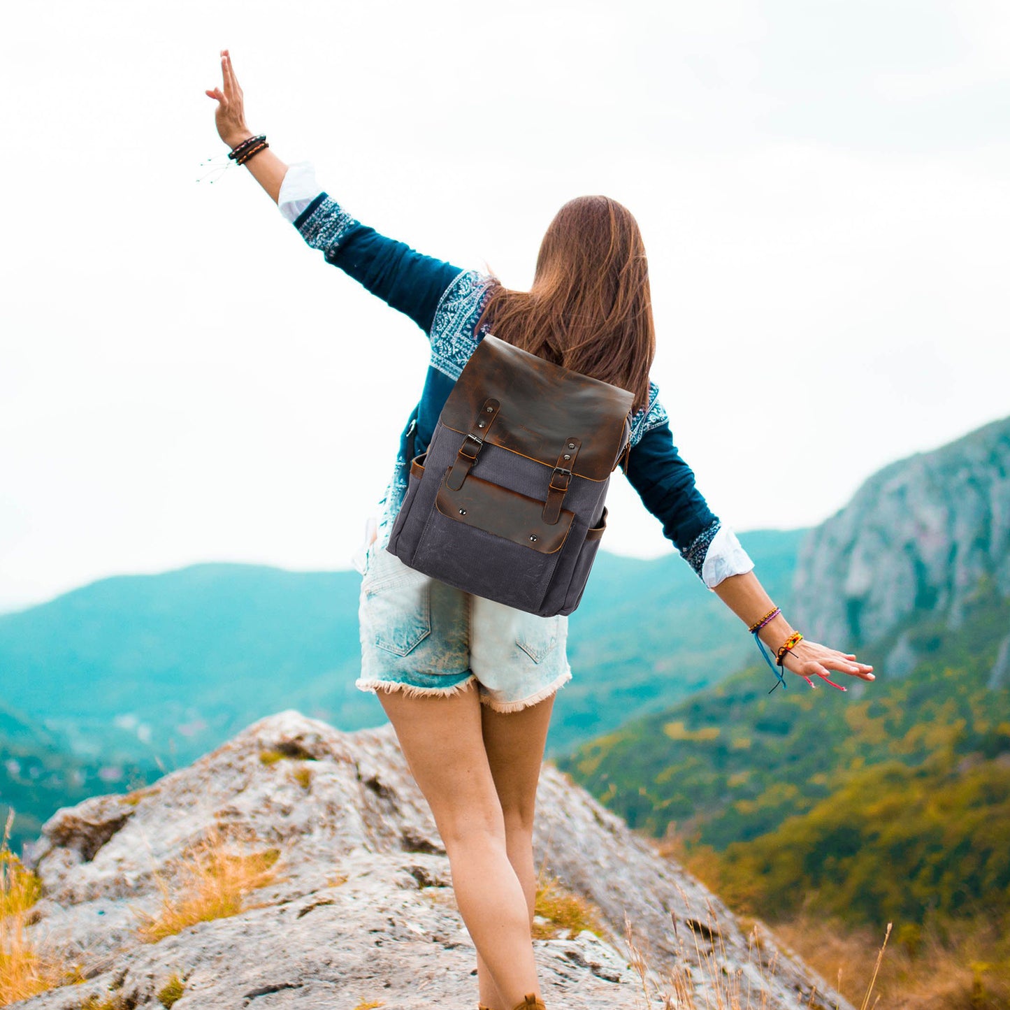 Person with a backpack standing on a mountain top with arms outstretched