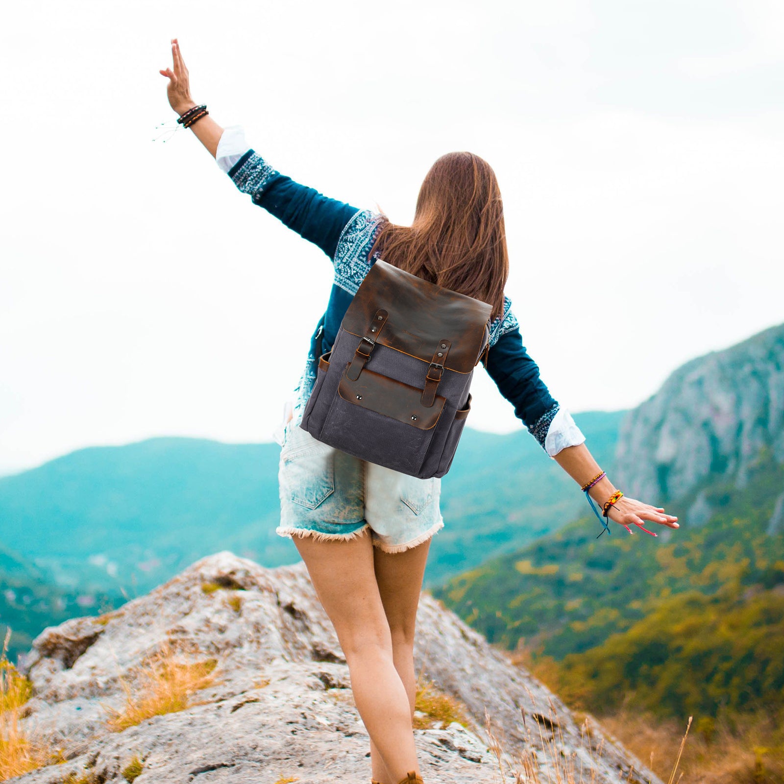 Person with a backpack standing on a mountain top with arms outstretched